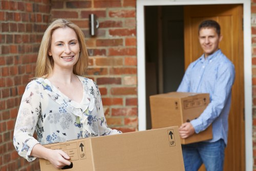 Two movers transporting household items into a removal van