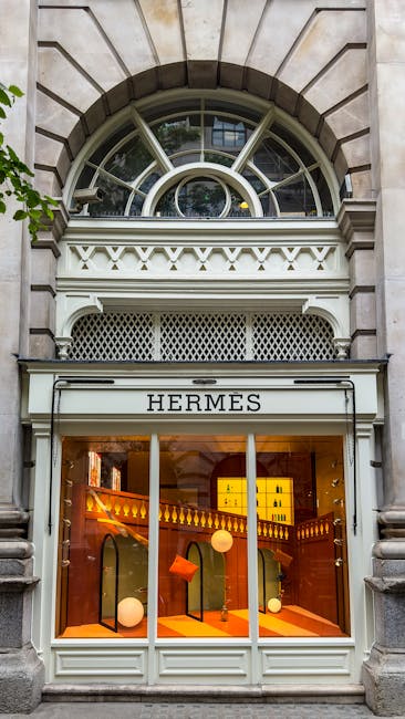 The image depicts the entrance to a listed Mayfair building with an ornate white stone archway framing a black door, set against a red-brick façade with decorative white stone details. Above the entr